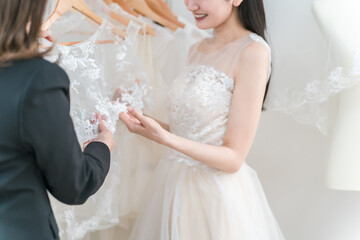 式場・ドレスショップでドレスを選ぶ新婦・花嫁とプランナーの女性
