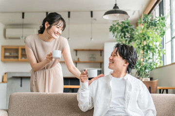 家のリビング・ソファで会話する仲良しの若い日本人夫婦
