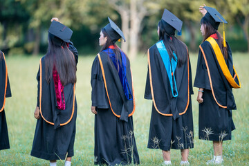 A group of women in graduation gowns are standing in a field