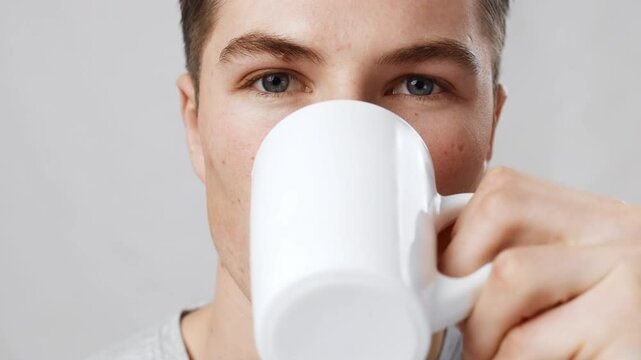 Sensitive teeth. Close up portrait of young man drinking hot coffee and feeling acute tooth pain, slow motion