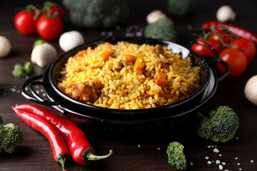 A plate with pilaf and ingredients, on a dark background.