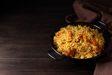 A plate with pilaf and ingredients, on a dark background.