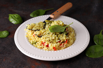 A plate with pilaf and ingredients, on a dark background.