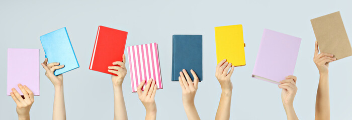 Many books in hands on a light background