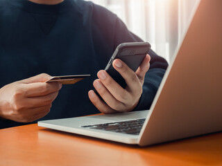 Secure payment concept. Black smart mobile smart phone in businessman hand while holding credit card for checking payment, online shopping, exchange or money transfer by finance application.