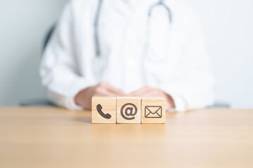 Contact Us concepts. Wood block of Email, call Phone and Website Address sign against Doctor...