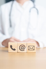 Contact Us concepts. Wood block of Email, call Phone and Website Address sign against Doctor...