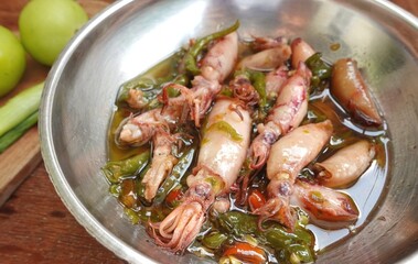Spicy squid dish with oily green chilies in a glass bowl.