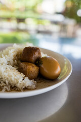 Stewed egg, tofu or eggs and pork in brown sauce with Thai rice. Thai name is khai palo muu saam chan.