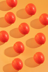 Red Tomato casting shadows on an orange background. Suitable for food and beverage blogs, healthy living websites, or fruitthemed designs.