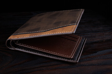 Brown leather wallet on a dark background.