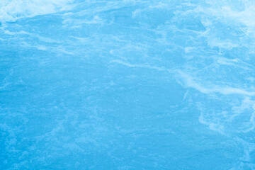 Blue water with ripples on the surface. Defocus blurred transparent blue colored clear calm water surface texture with splashes and bubbles. Water waves with shining pattern texture background.