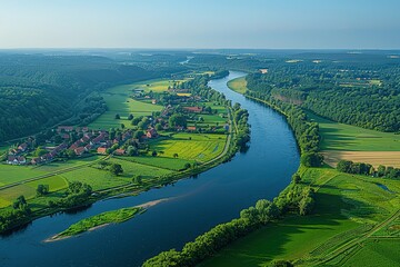 A river runs through a lush green valley with a small town on one side
