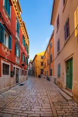 Rovinj, Croatia - Traditional colorful houses on an empty narrow cobblestone street at the Old Town of Rovinj in a sunny summer morning with clear blue sky