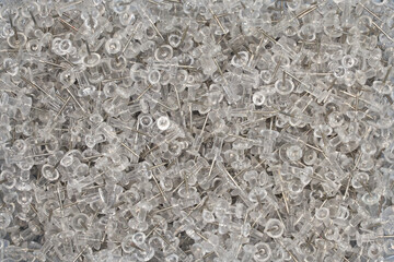 A close up of thousands of clear transparent office or craft wall pins. Thumb pins or wall tacks.