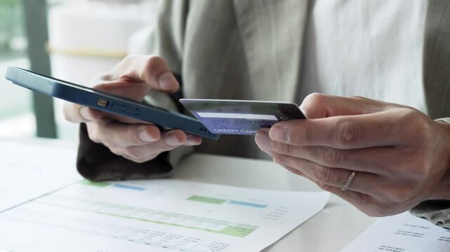 Asian male holding credit card and using smartphone for online payment