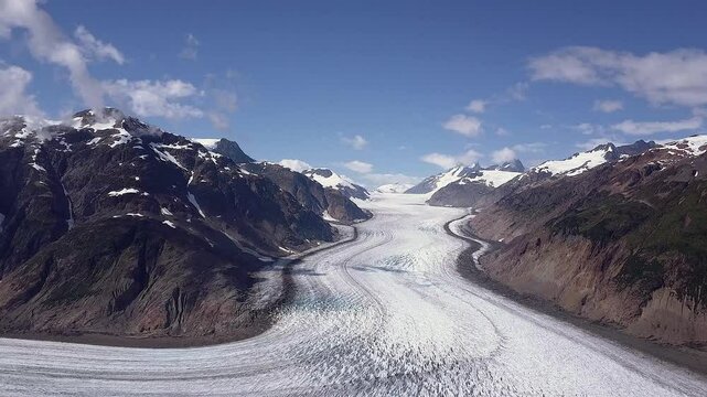Aerial: Highly textured glacier in mtns below copy space blue sky