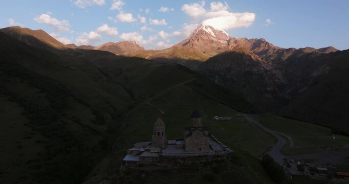 Drone Circles Above Gergeti Trinity Church. Mount Kazbek in Background Sunrise.