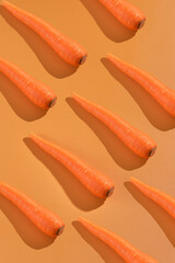 Carrots arranged in diagonal pattern on orange background. Fresh produce, healthy eating, food styling, recipes, vegetarian cuisine, farm market