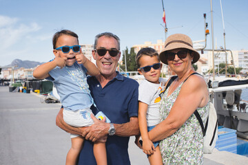 Family Enjoying Sunny Day at Gandia Harbor with Boats in Background.