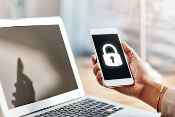 Hand, smartphone screen and lock icon in office with laptop, display and ux for cybersecurity software. Person, phone and computer with symbol, protection and safety from virus, phishing and hacking