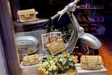 Naklejka premium Siena, Italy-June 22,2024: The iconic VESPA scooter in a women's bag shop window, blending fashion with Italian charm.