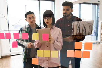 Collaborative team brainstorming session with sticky notes and digital devices. Diverse coworkers discussing ideas, strategies, and project development in modern workspace.