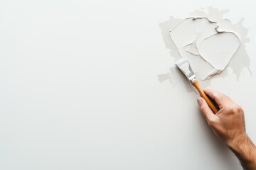 Hand using a putty knife to spread spackle on a wall. DIY home repair and renovation concept with white background and copy space.