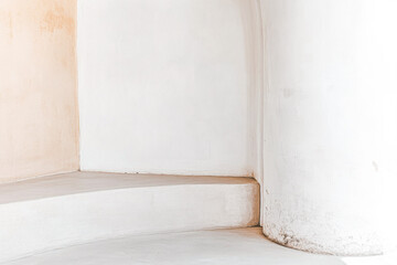 Curved white walls and an elegant column create a serene corner in a minimalist space during daylight hours