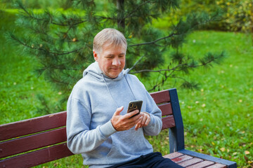 Mature man with mobile phone resting after workout in park