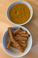 Brown and powdered cinnamon sticks and anise in white bowl