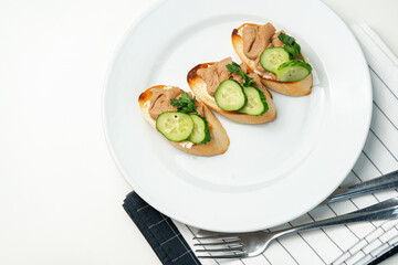 Savory canapes topped with creamy spread and cucumber slices served on toasted bread at a casual gathering