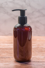 A brown bottle of beard shampoo on a wooden table and light background.