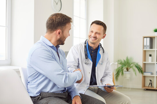 Doctor or nurse shakes hands with a male patient during visit to the hospital clinic. The handshake symbolizes professional medical care, trust, and the importance of patients healthcare.