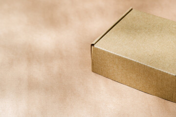 A plain cardboard box on a textured surface with soft light and shadows during the afternoon