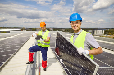 Portrait of a happy electrician working on the roof during the installation or servicing of solar...