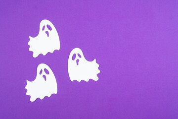 Decorative white ghosts on vibrant purple background for Halloween festivities