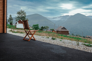 A wooden chair overlooks a serene mountain landscape at dawn with mist covering the hills in the background