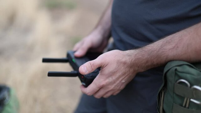 A soldier controls a FPV drone close-up, the control panel in his hand