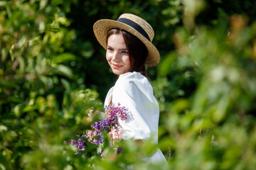 Portrait of a girl in a straw hat with lupine flowers in nature