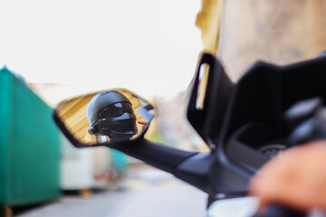 man fastens a black helmet on his head in a mirror