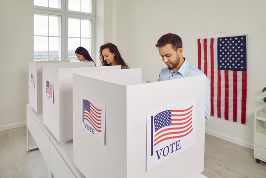 American citizens people USA voters standing in a row at polling station at vote center with us flags going to put their ballots in voting booth. Democracy and election day concept.
