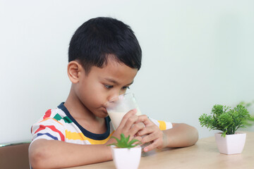 Asian little cute boy drinking milk. stays home with a smiling face, feels happy, and enjoys...