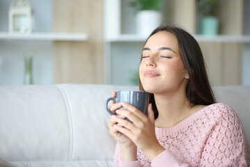 Woman relaxing smelling coffee or tea at home