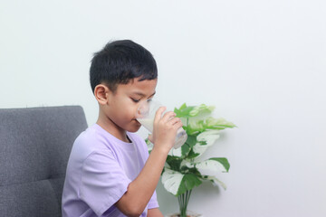 Asian little cute boy drinking milk. stays home with a smiling face, feels happy, and enjoys drinking milk.