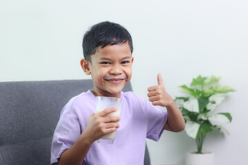 Asian little cute boy drinking milk. stays home with a smiling face, feels happy, and enjoys...