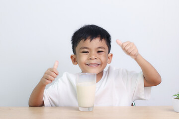 Asian little cute boy drinking milk. stays home with a smiling face, feels happy, and enjoys...