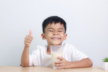 Asian little cute boy drinking milk. stays home with a smiling face, feels happy, and enjoys...