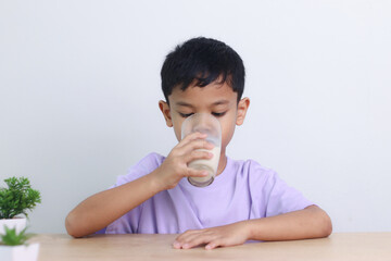 Asian little cute boy drinking milk. stays home with a smiling face, feels happy, and enjoys...