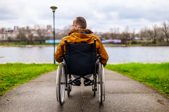 Rear view image of paraplegic handicapped man in wheelchair by the lake.